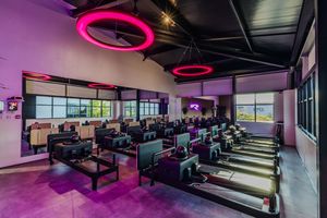 Modern esports gaming center with pink LED lighting, tiered seating, and multiple gaming stations in a sleek black interior.
