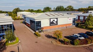 Panoramic aerial view of industrial warehouses and business buildings in a commercial park with paved parking areas.