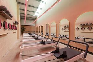 Pink-walled fitness studio with mirrored walls and ballet barres mounted along the perimeter for dance and exercise classes.