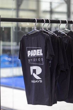 Black t-shirts with minimalist logos and branding displayed on retail clothing rack in store.
