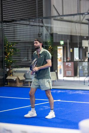 Person playing on an indoor blue sports court wearing casual athletic attire.