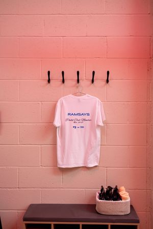 A sequence of photos showing a white t-shirt hanging on a pink wall in different positions and lighting conditions.