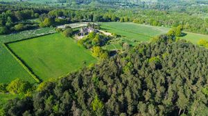 Aerial panoramic view of lush green countryside with rolling hills, forests, and agricultural fields in springtime.