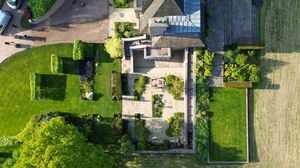 Top-down drone view of a residential property with manicured lawns and agricultural fields nearby.