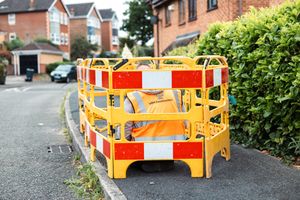 Yellow and red traffic barriers with reflective markings line up along a residential street.