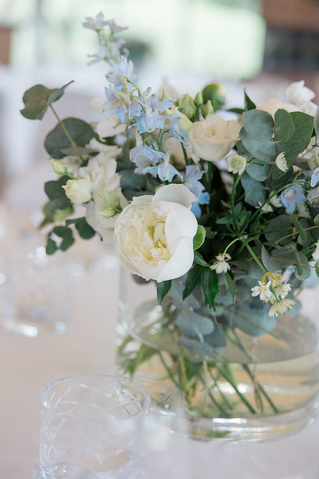 Black and white view through doorway of elegant wedding reception setup with white tablecloths and chandelier lighting.