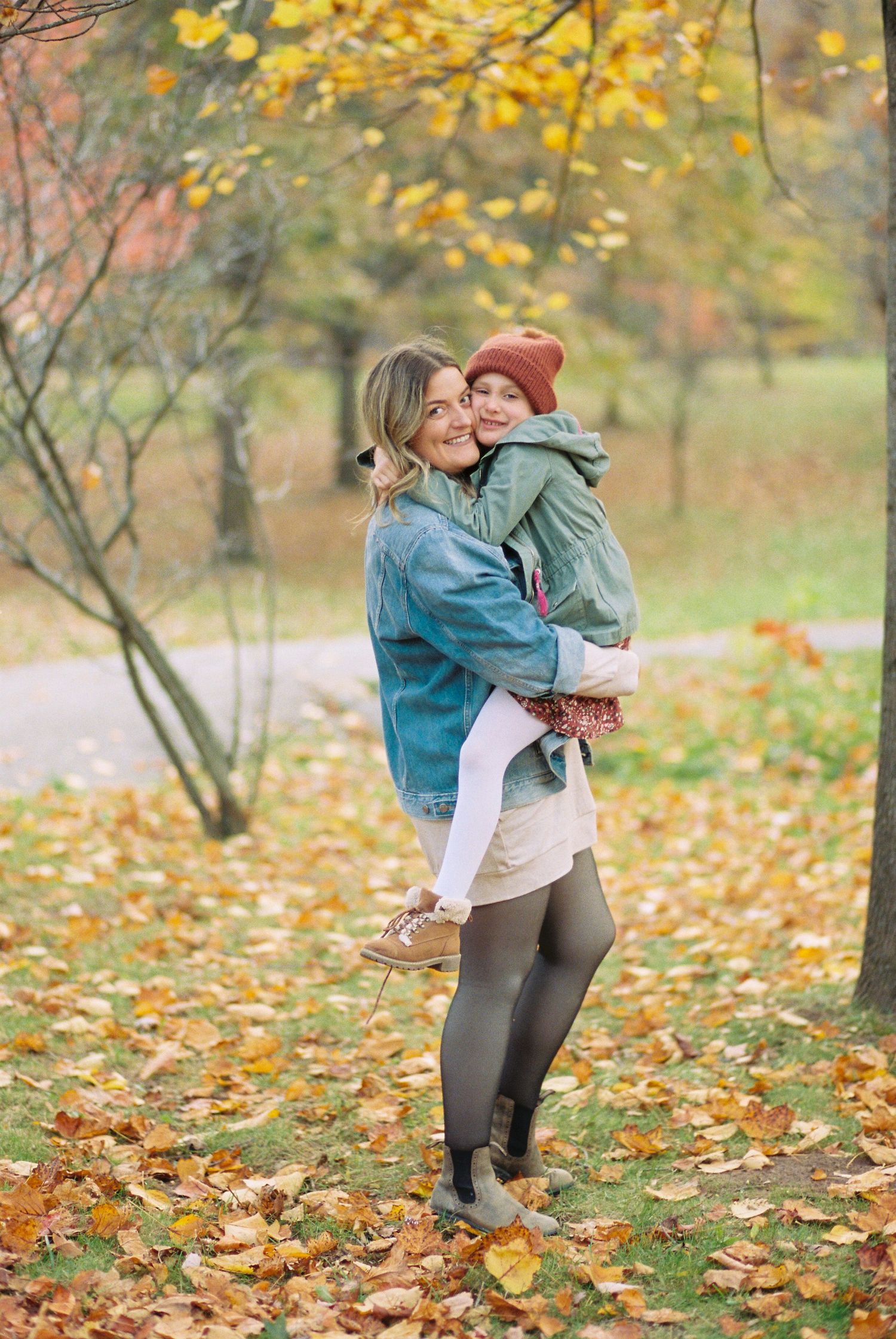 Autumn engagement photoshoot among yellow falling leaves in a park setting.