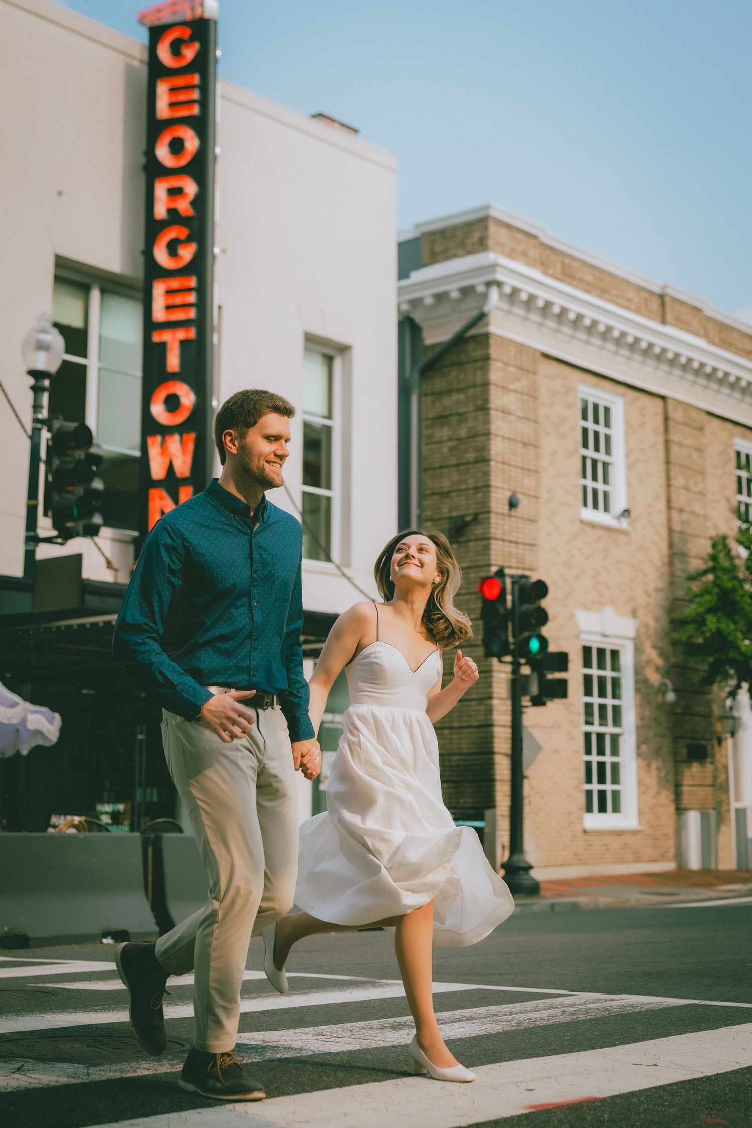 A romantic couple runs through the streets in front of the iconic Georgetown neon sign in Washington, DC