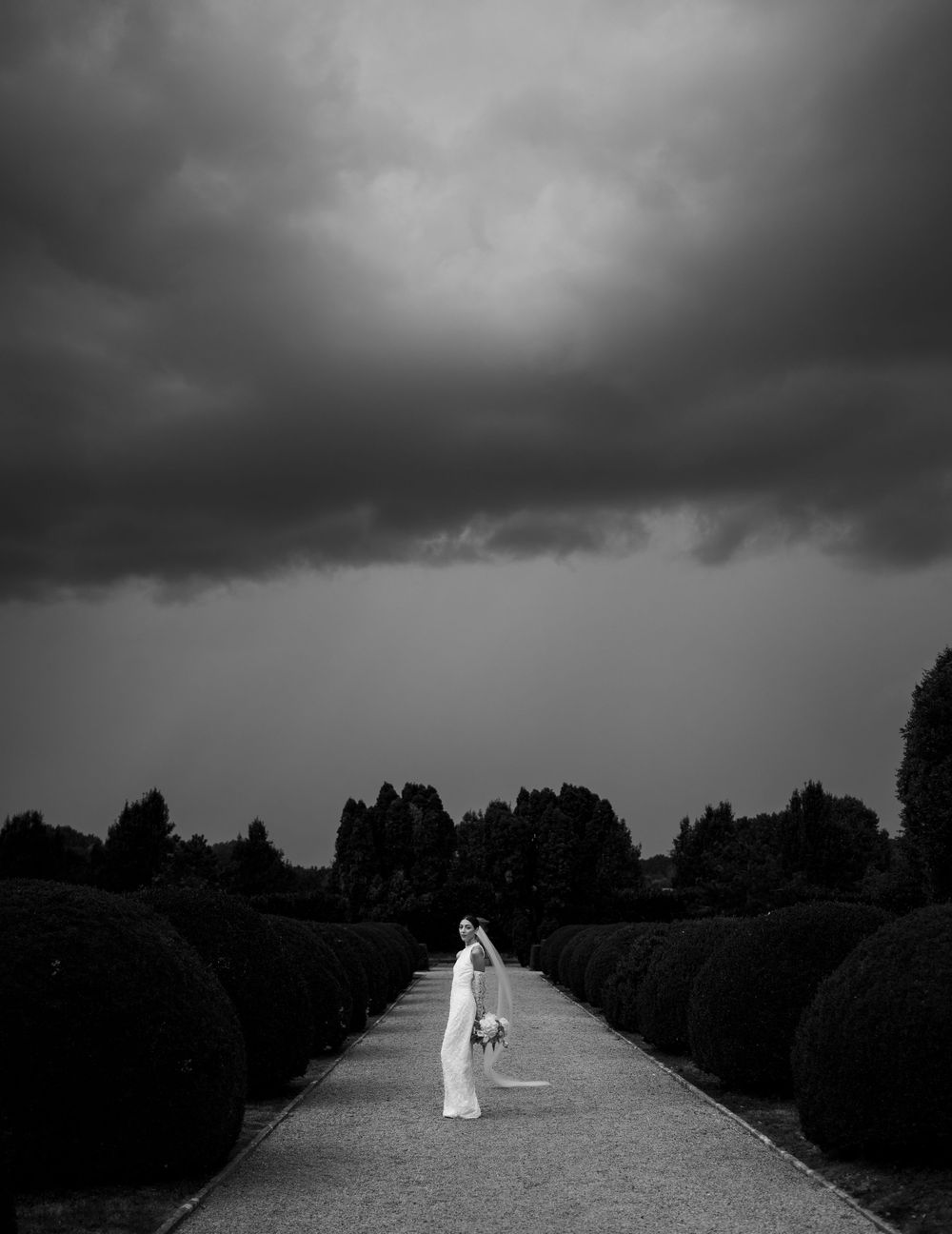 A dramatic black and white landscape with a path leading through stormy skies.