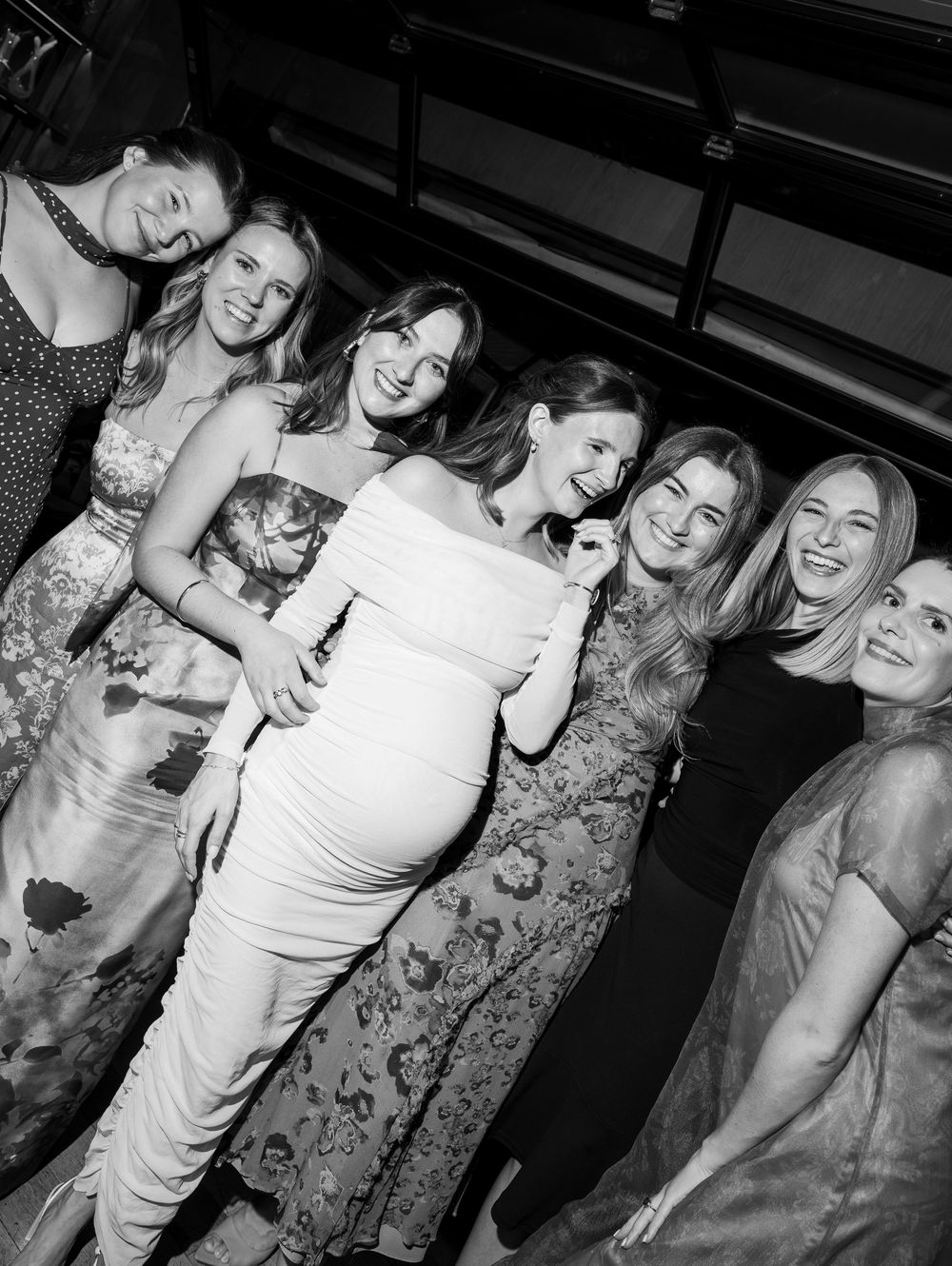 Group of women smiling and posing together at a formal event, black and white photo.