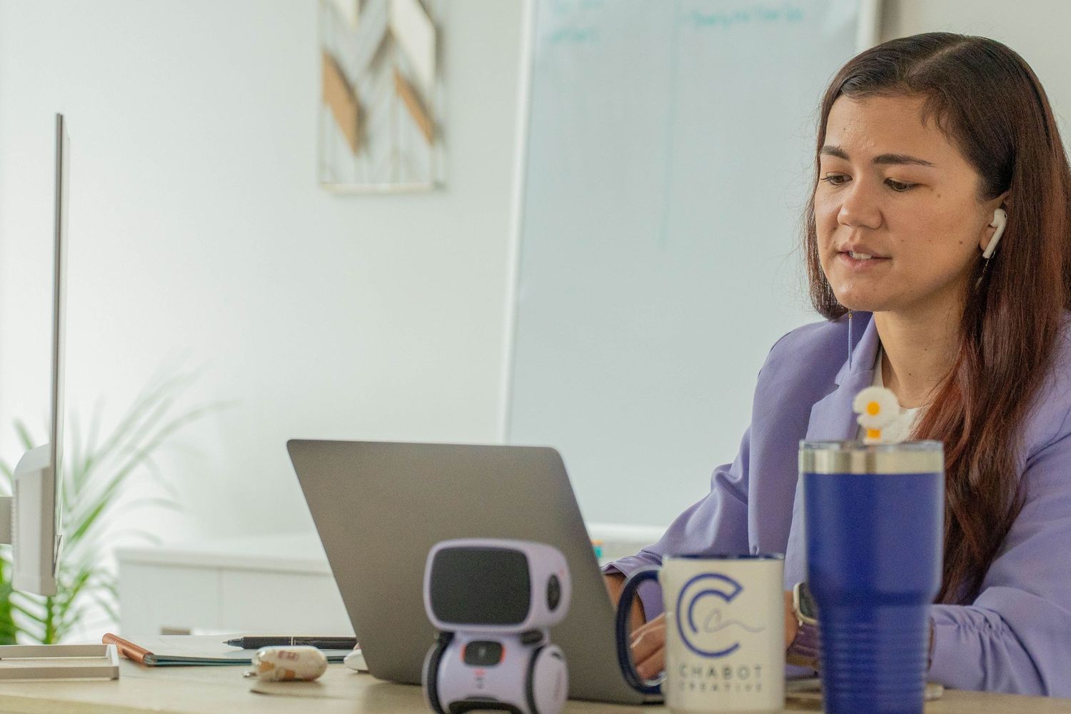 Professional workspace with laptop, water bottle, and office supplies on white desk.