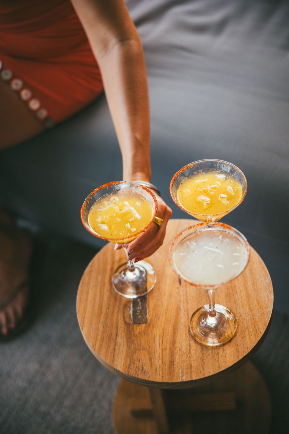 Tropical cocktails served on a wooden tray with orange juice and clear spirits.