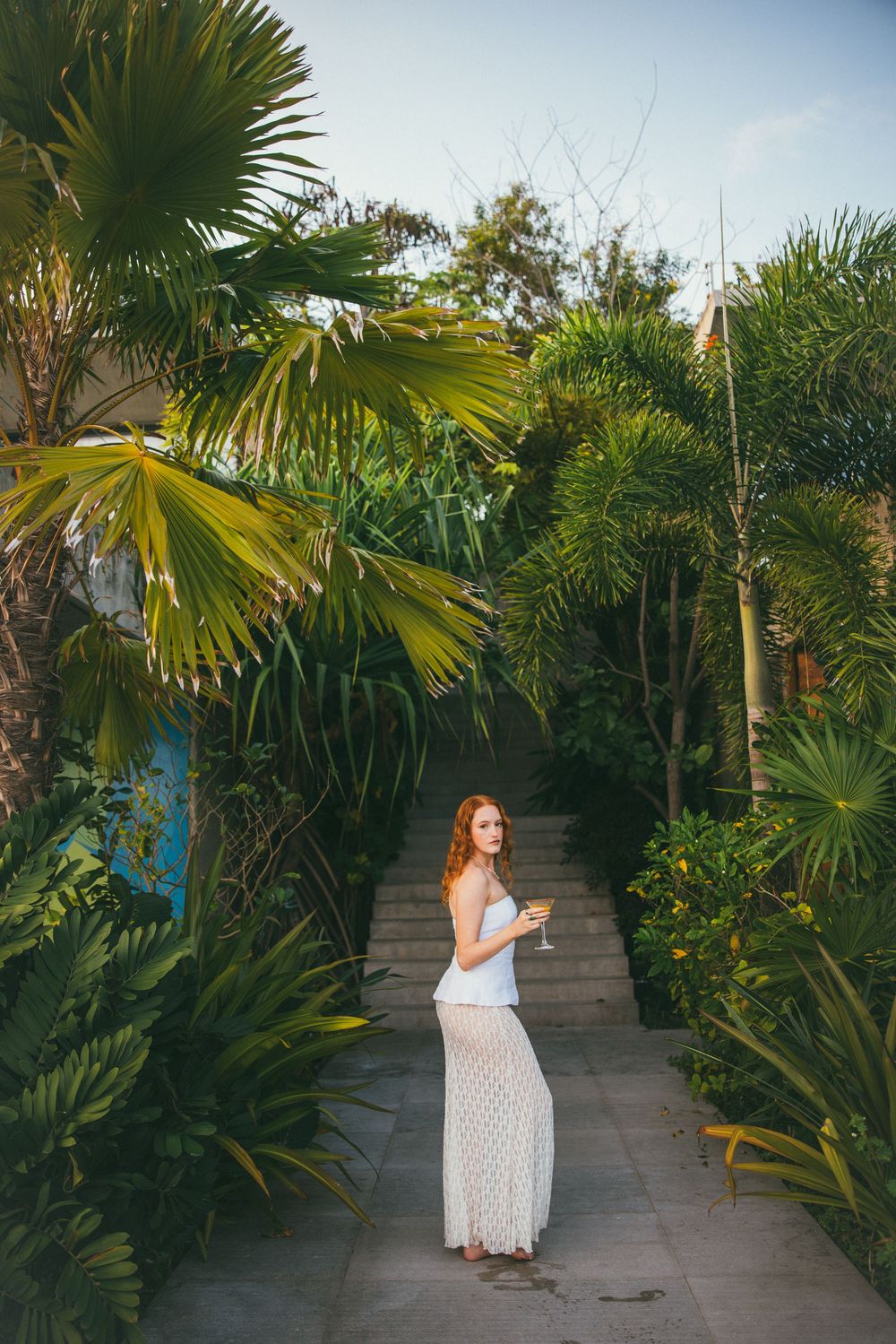 Lush tropical garden pathway lined with palm trees and greenery creates an exotic paradise setting.