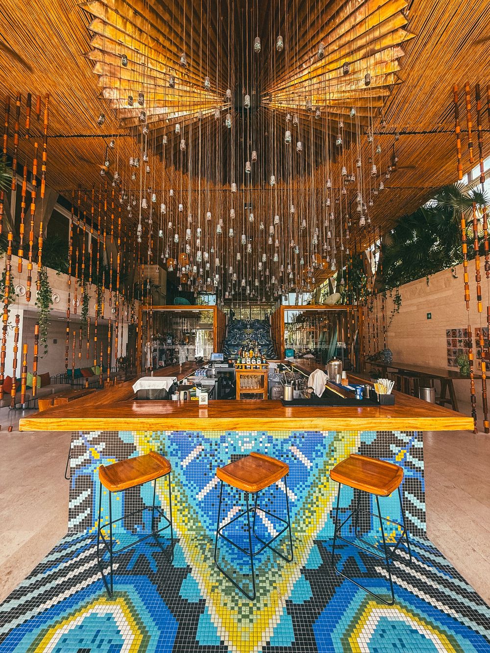 Decorative hanging lights illuminate a rustic venue with exposed brick walls and vibrant blue geometric patterns.