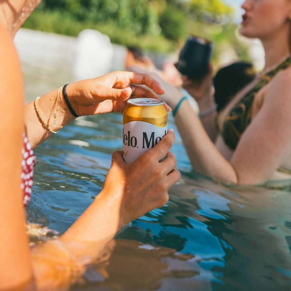 Friends enjoying drinks and conversation in a swimming pool during summer.