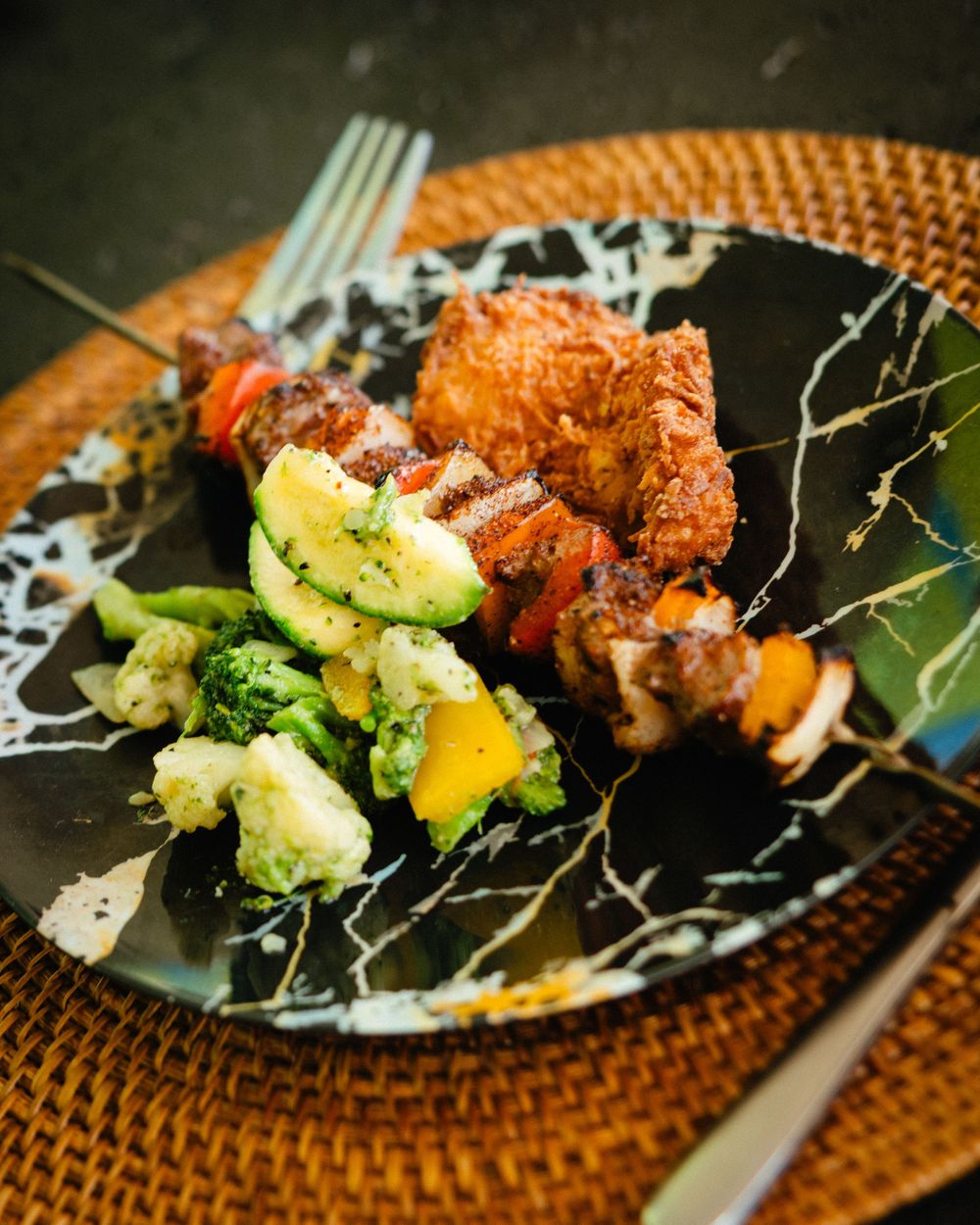 Gourmet dish featuring crispy orange chicken and fresh avocado on a decorative plate.