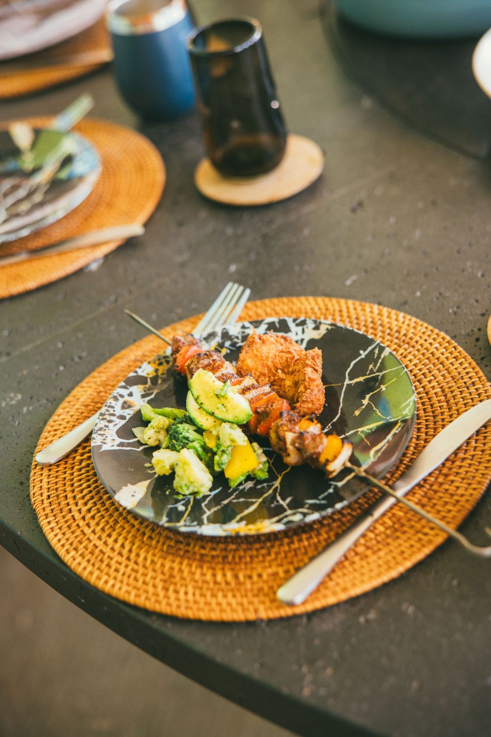 Elegant plated meals served on orange woven placemats with fresh salads and garnishes.