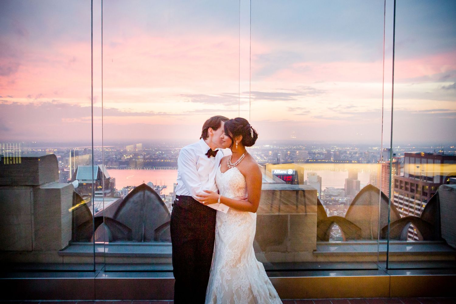 Sunset wedding photos with city skyline views through large windows.