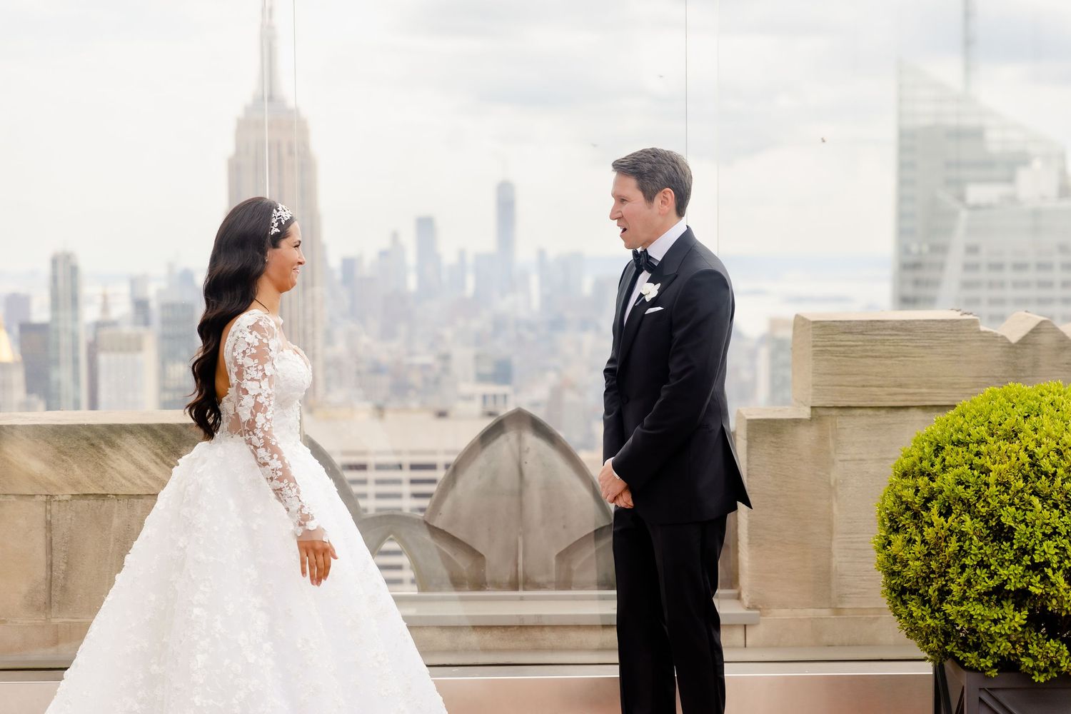 Wedding couple standing on rooftop with dramatic city skyline backdrop during first look photo session.