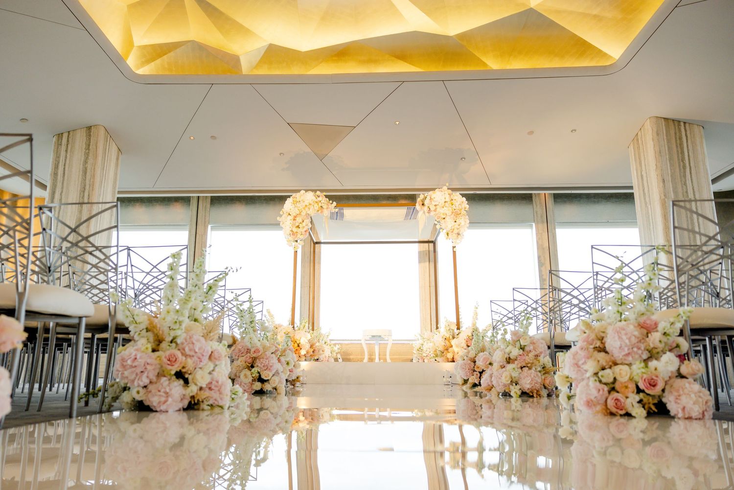 Modern wedding reception space with illuminated ceiling and floor-to-ceiling windows.
