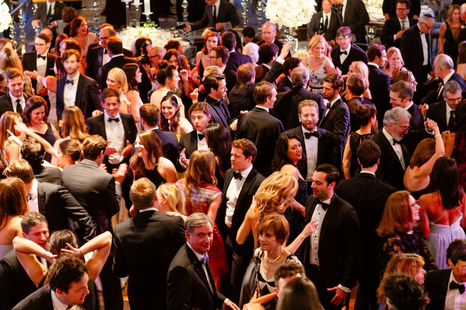 A crowded formal event shows a large group of people mingling and socializing in formal attire.