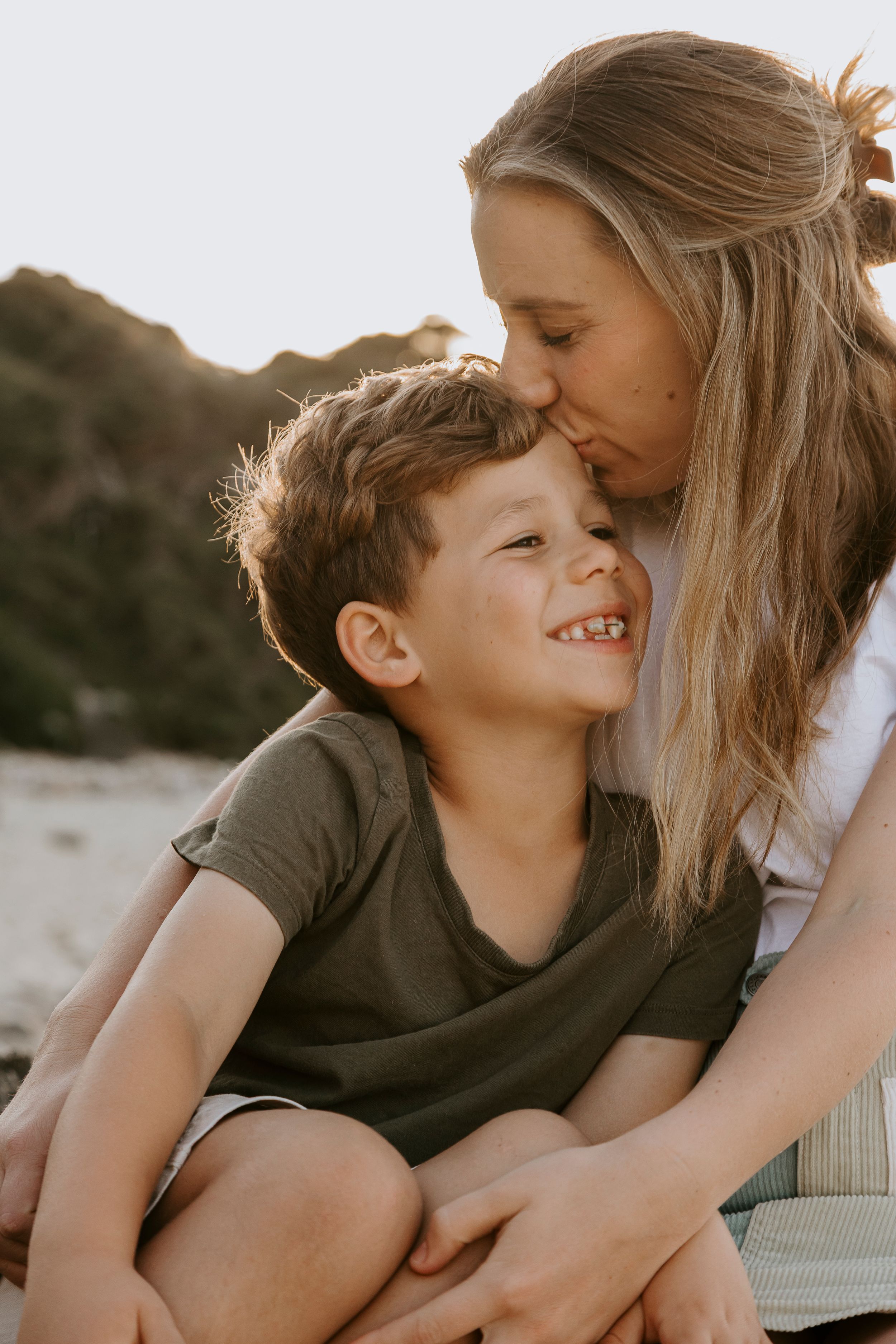 A tender family moment captured during golden hour at sunset showing affection and laughter.