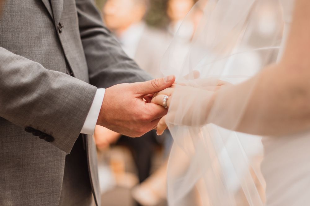 Close-up shot of hands exchanging wedding rings during an elegant ceremony.