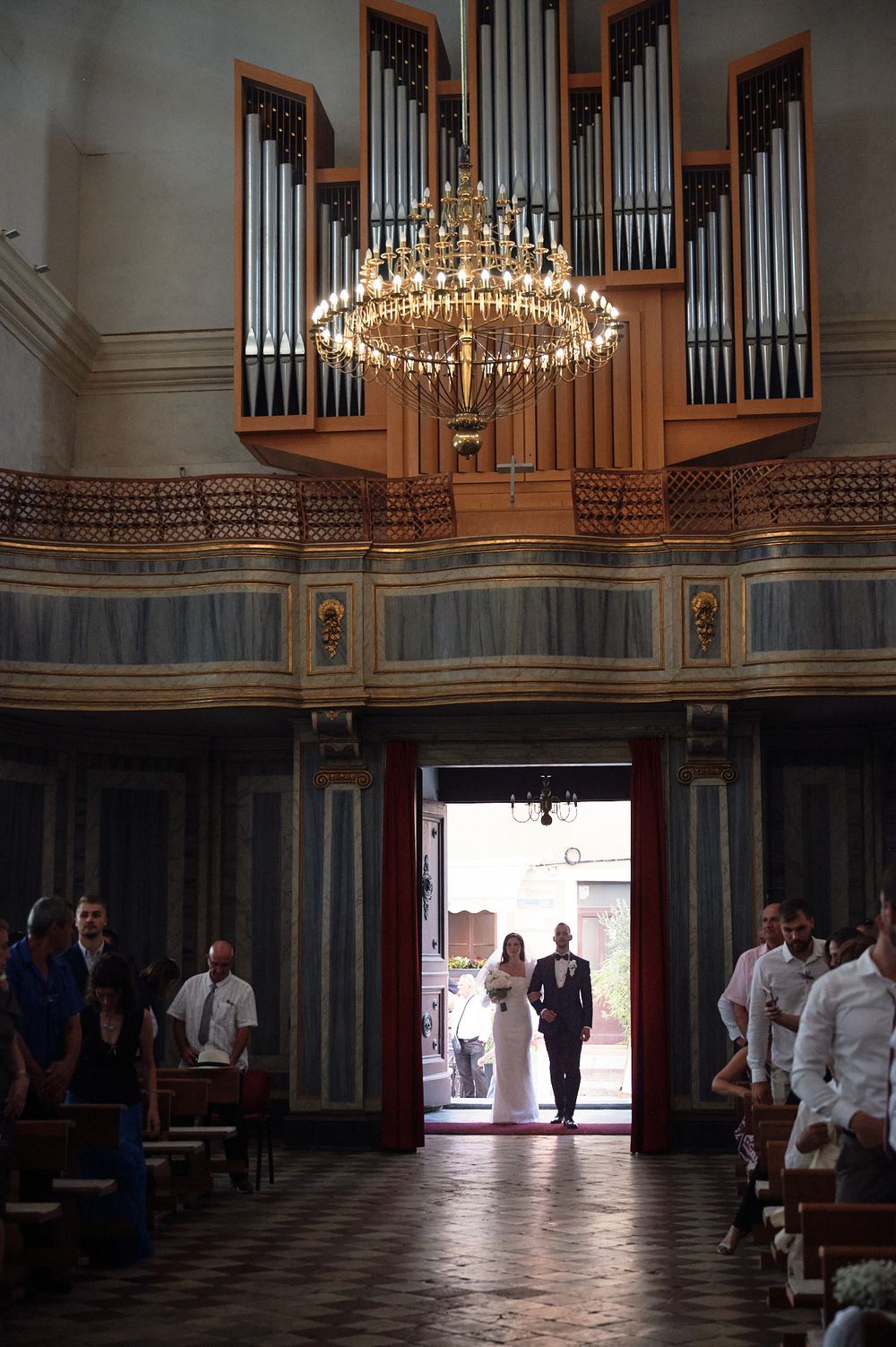 Wedding ceremony venue interior with elegant chandelier and pipe organ in a grand hall.