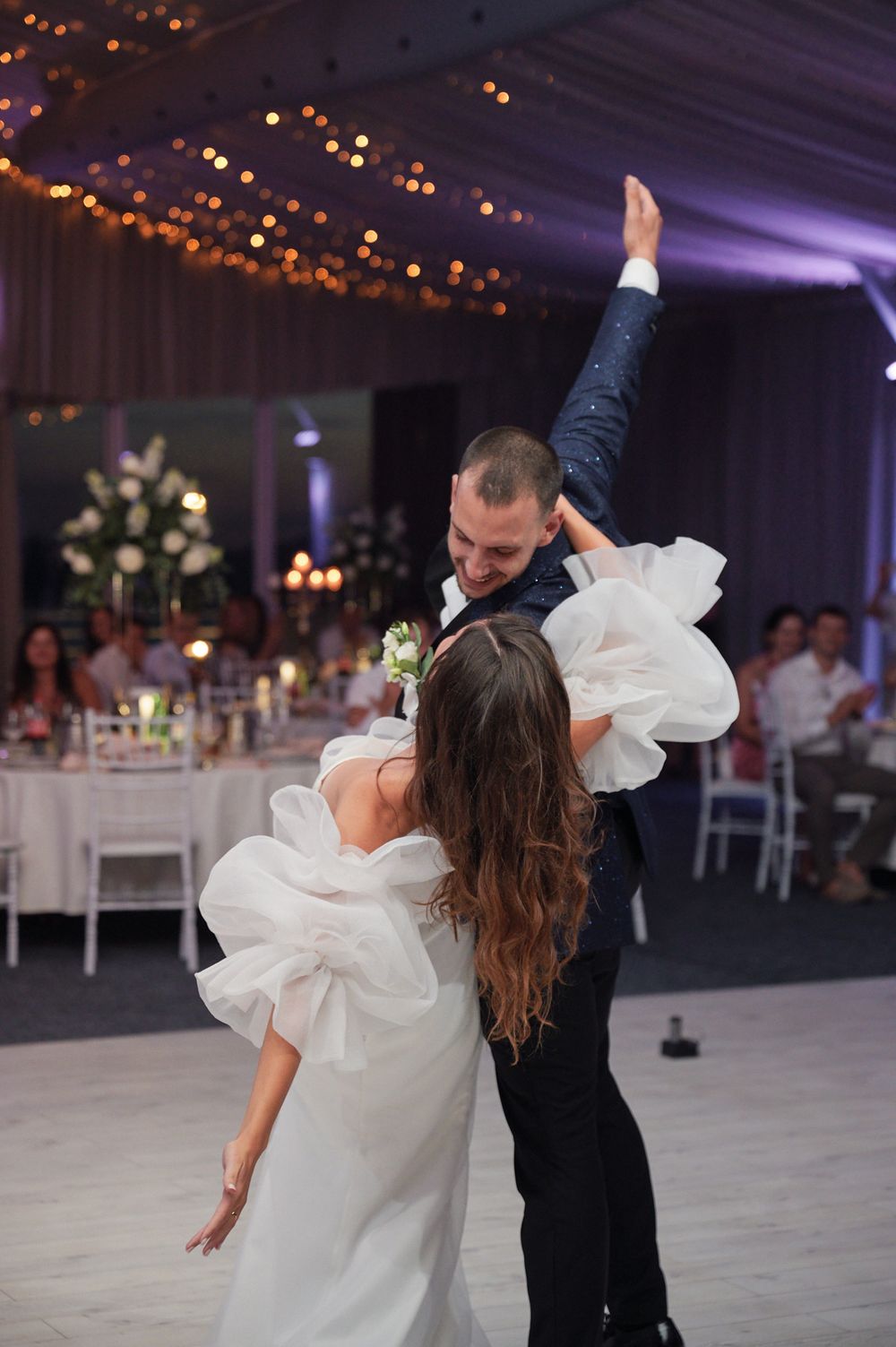 Romantic dance sequence showing couple in wedding attire performing dramatic dip moves under purple mood lighting.