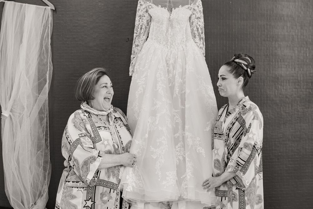 Vintage black and white photograph showing a series of delicate white lace dresses and christening gowns on display.