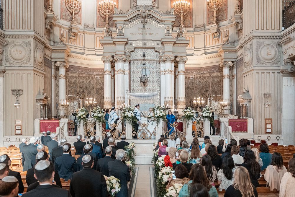 Elegant wedding ceremony taking place in an ornate baroque church with crystal chandeliers and marble columns.
