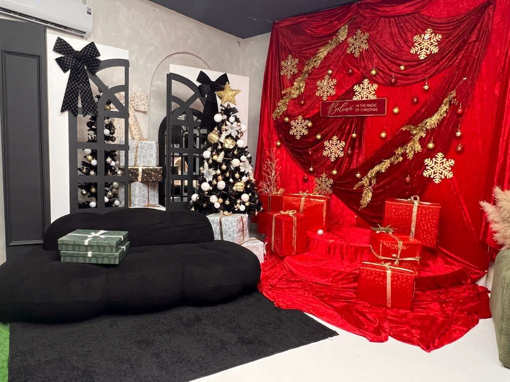 Elegant black and red Christmas photo studio set with gold snowflakes, decorated tree, and wrapped presents.
