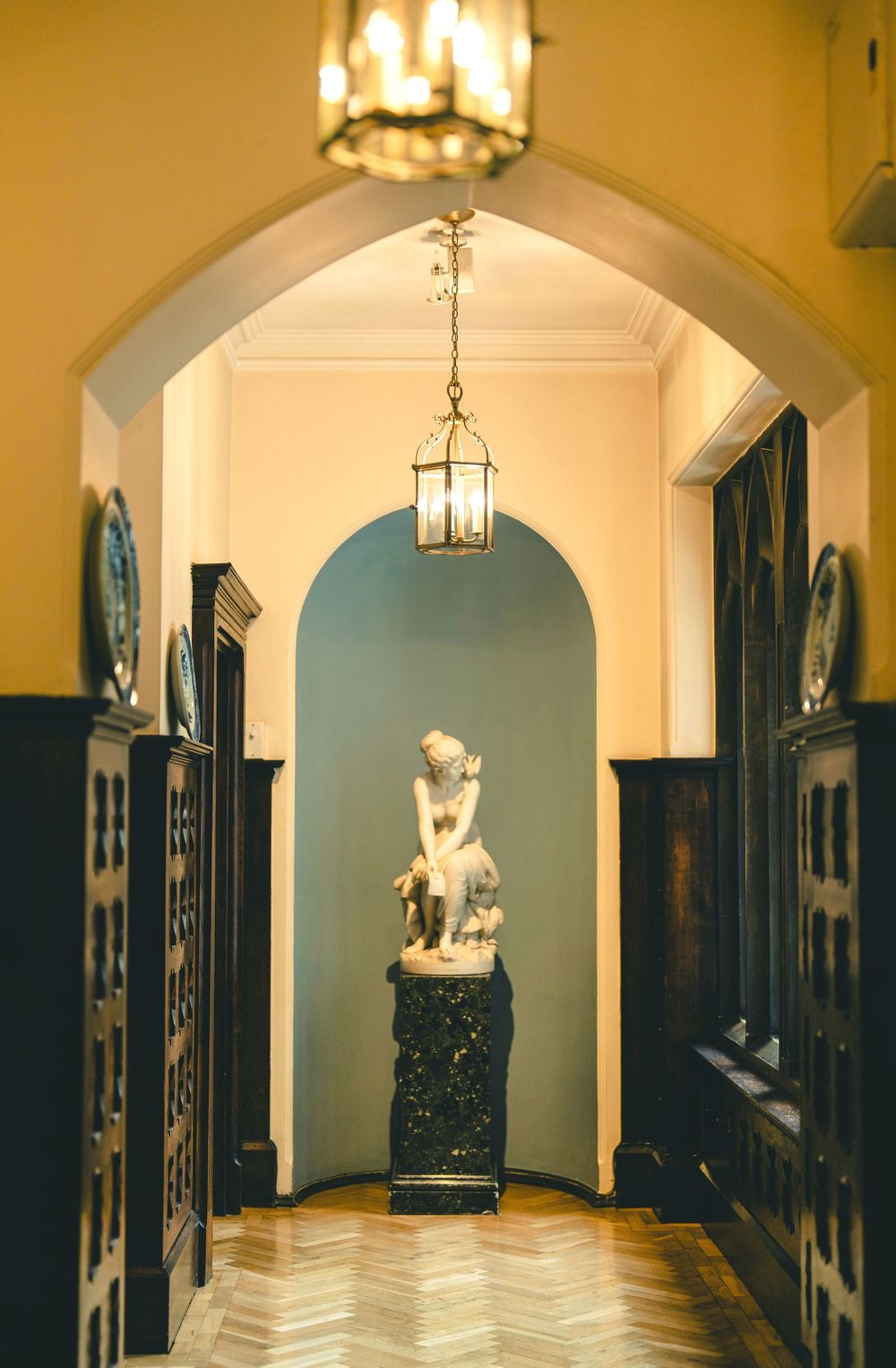 Elegant hallway with arched ceilings and hanging lanterns in warm golden lighting.
