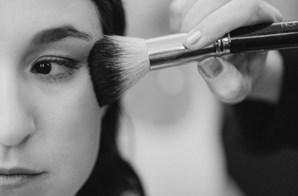 Makeup artist applying cosmetics with brushes in preparation for special event.
