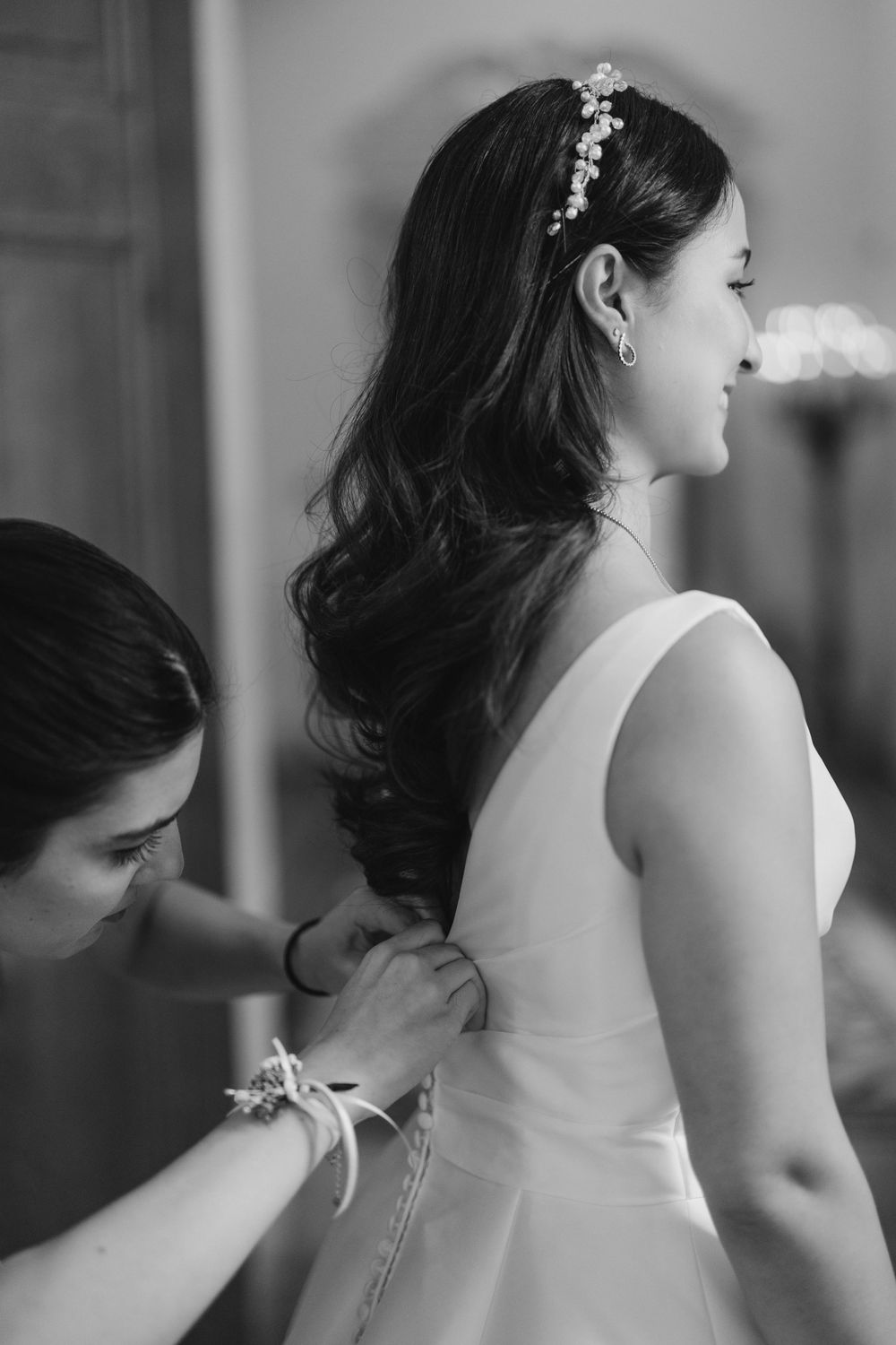 Close-up of white wedding dress details and hair accessories in black and white.