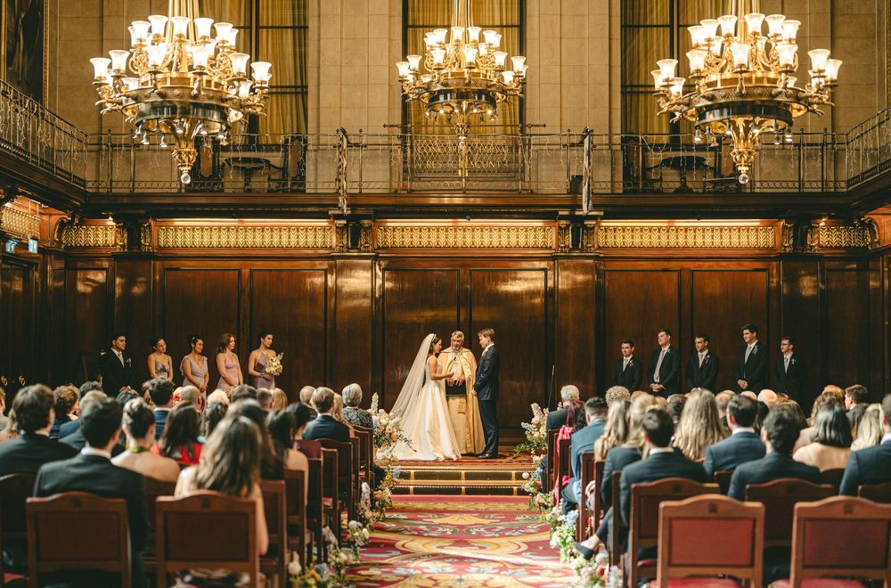 Grand ballroom with crystal chandeliers and rows of seating for formal event.