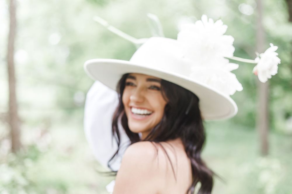Joyful outdoor portraits with a classic white sunhat and natural woodland backdrop.
