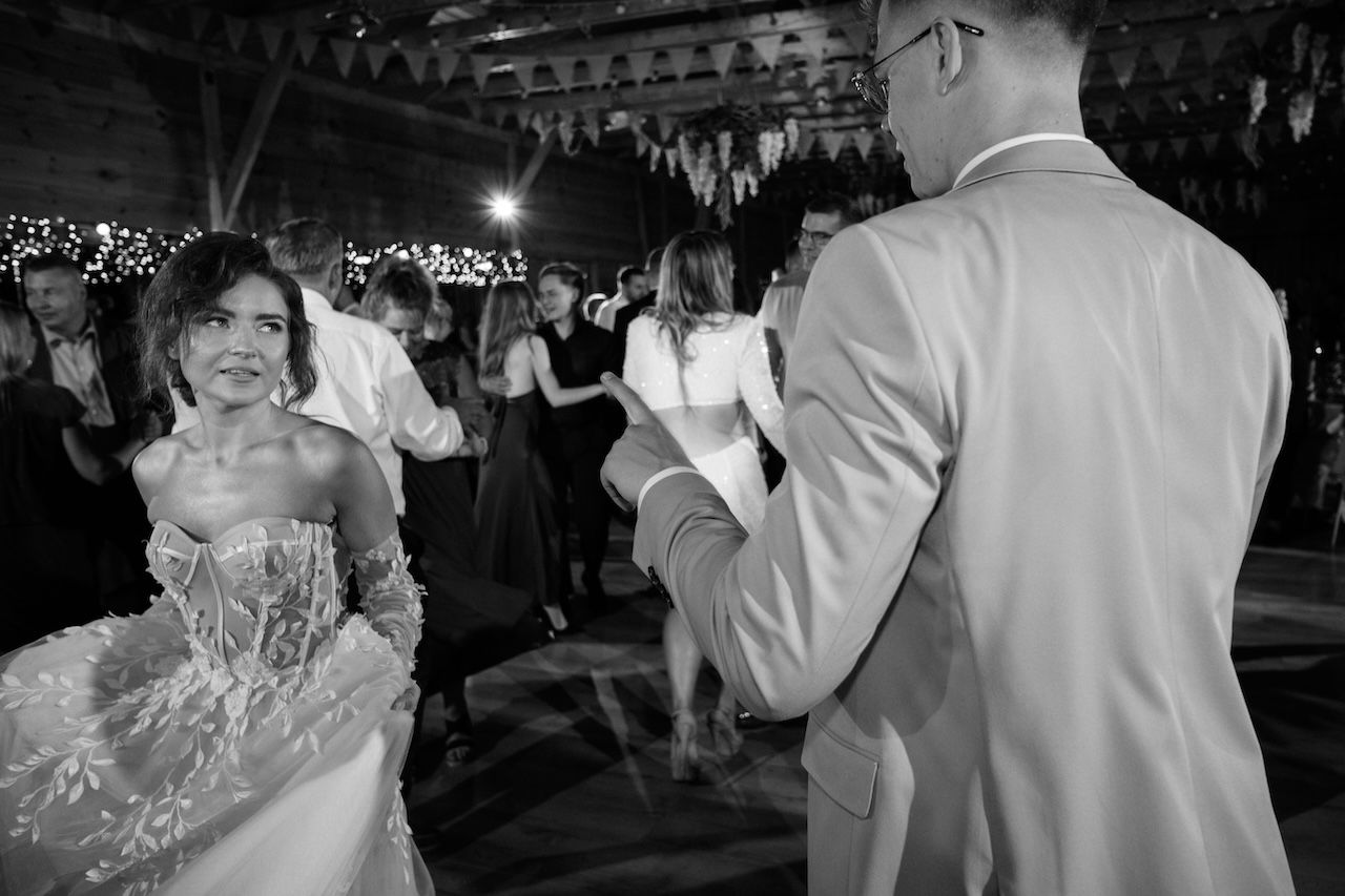 Black and white photo of smiling bride dancing with groom at wedding reception.