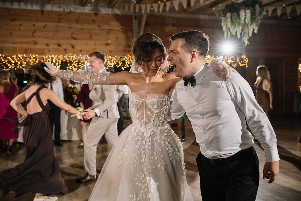 Bride and groom sharing an energetic dance together at their rustic barn wedding reception.