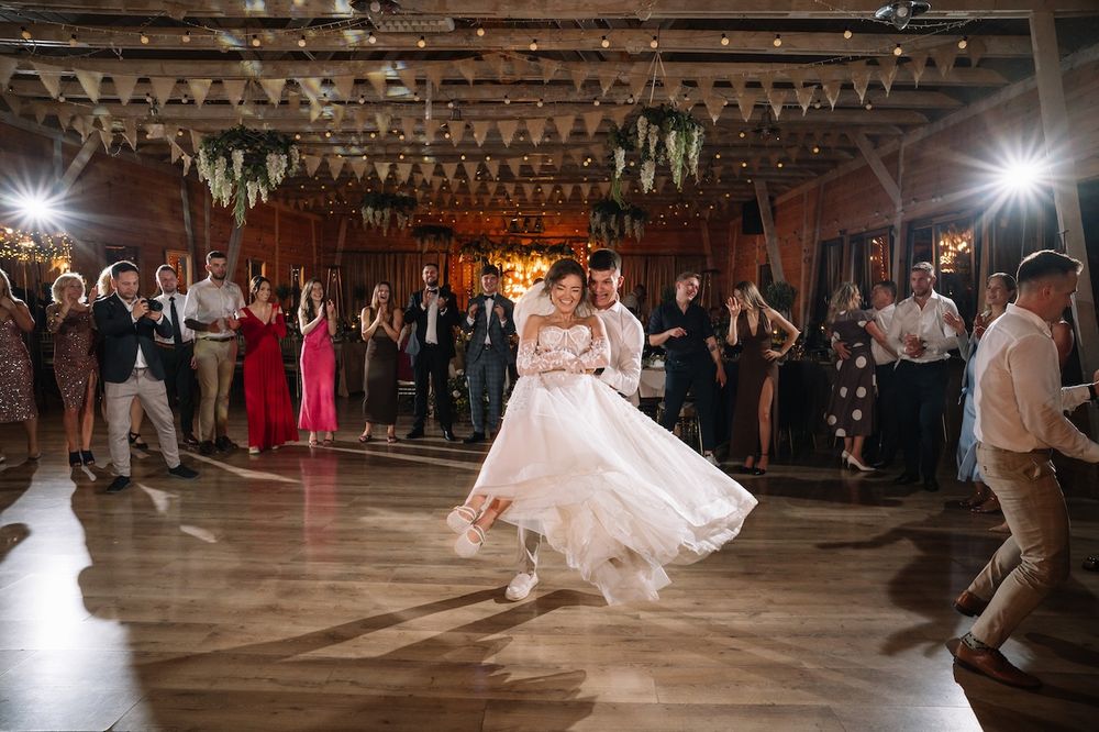Bride and groom sharing their first dance as guests watch at a rustic barn wedding.