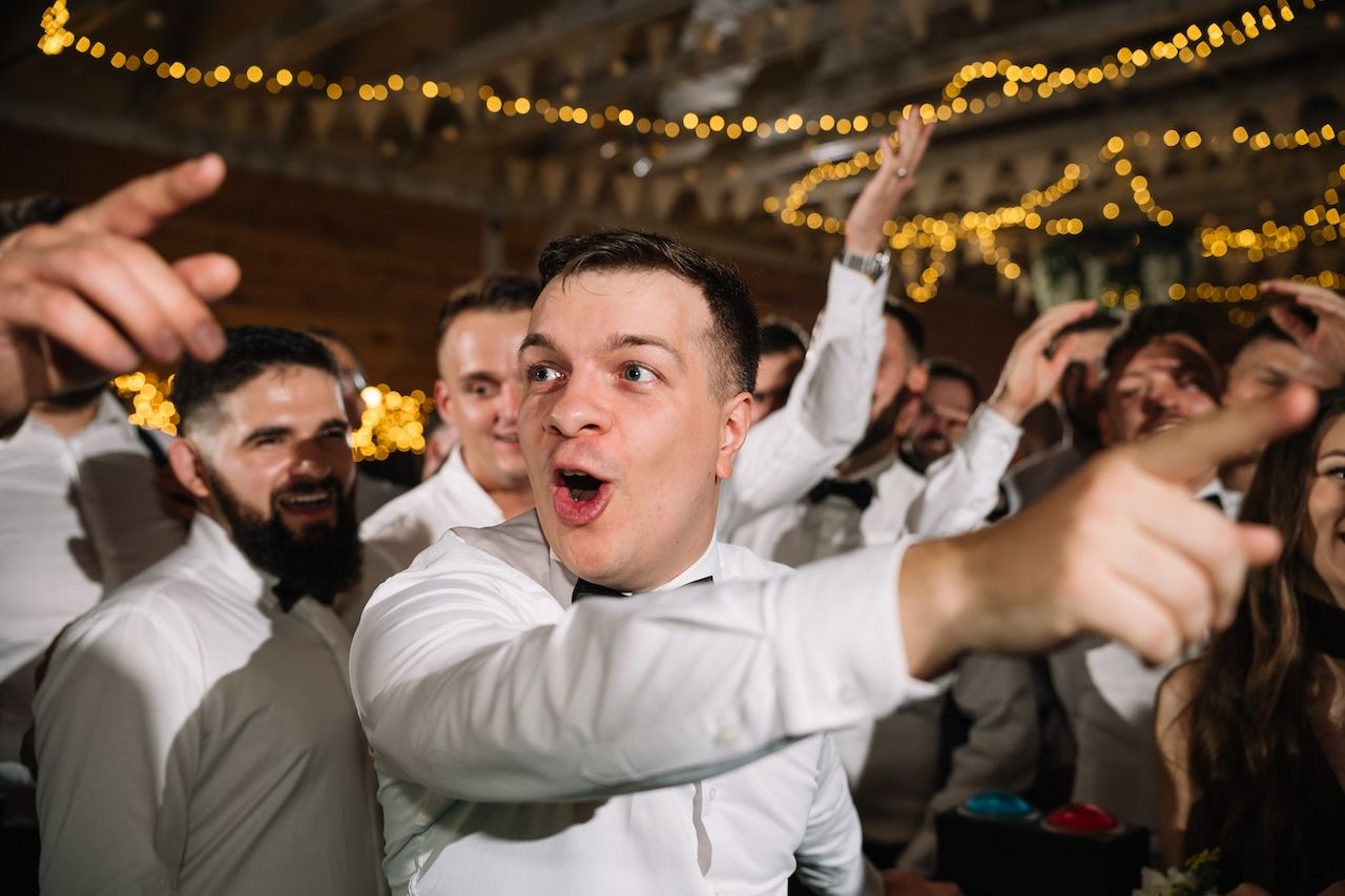 Excited wedding guest pointing enthusiastically while celebrating on the dance floor.