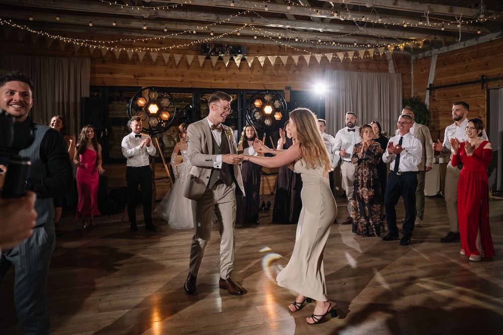 Couple dancing together on the dance floor surrounded by wedding guests at reception.