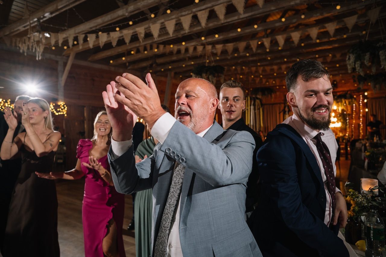 Excited wedding guests clapping and cheering on the dance floor at a reception.