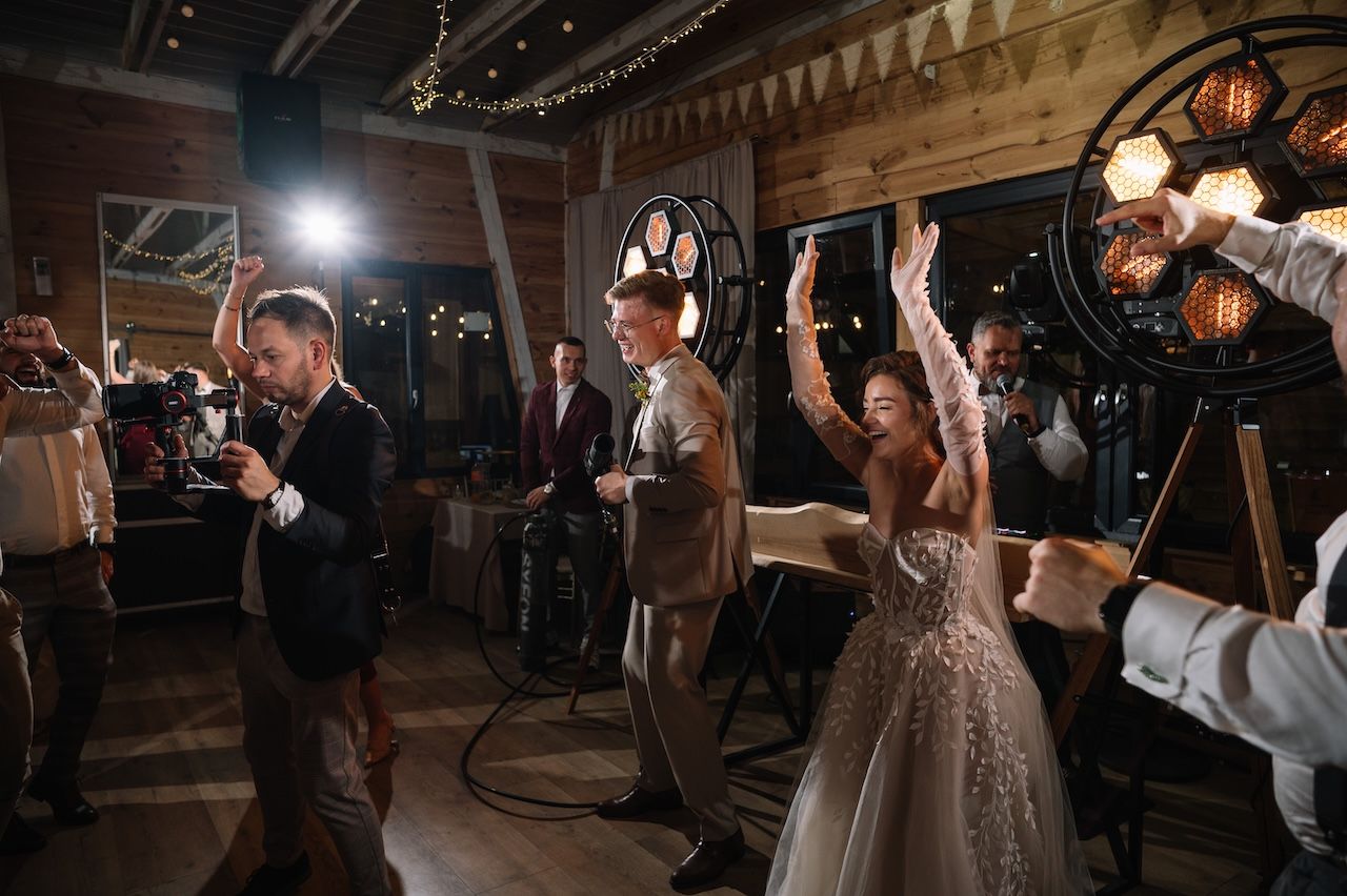 Bride and groom celebrating with raised hands at a rustic wedding reception with vintage decor.