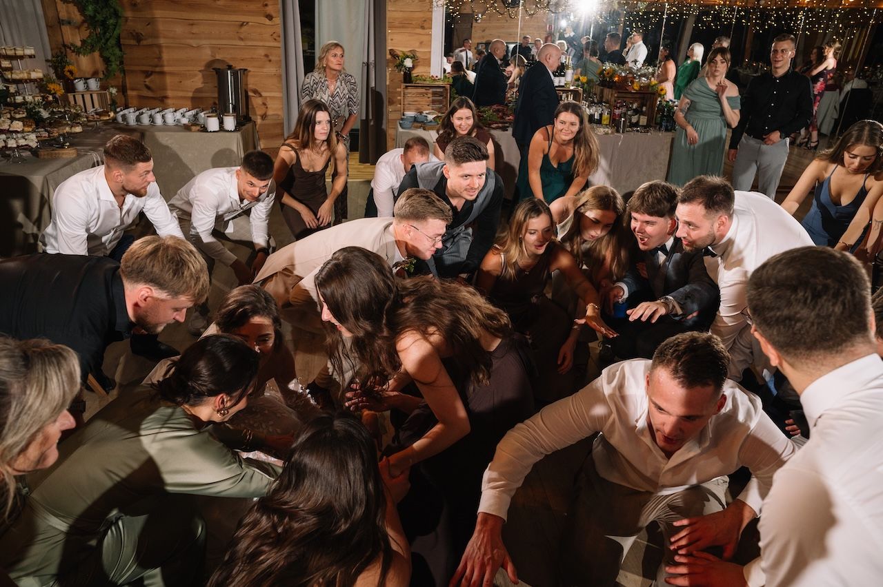 Wedding guests forming a huddle and dancing together in a circle at a lively reception.