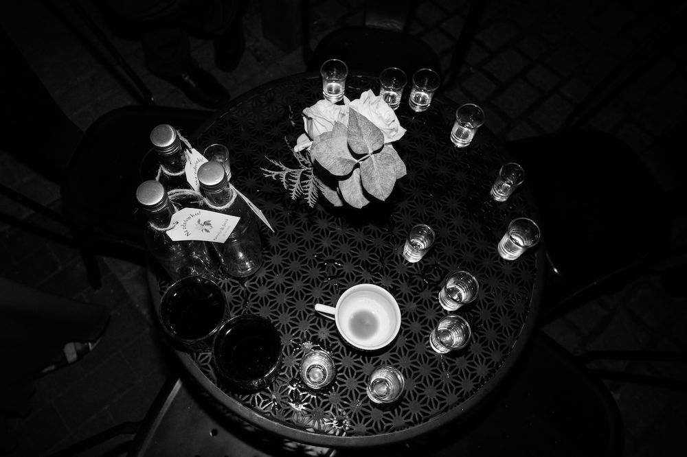 Black and white overhead view of elegant wedding reception table with glasses and bottles.