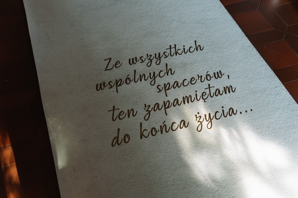 Wedding aisle runner with Polish inscription reading a romantic quote in elegant gold lettering.