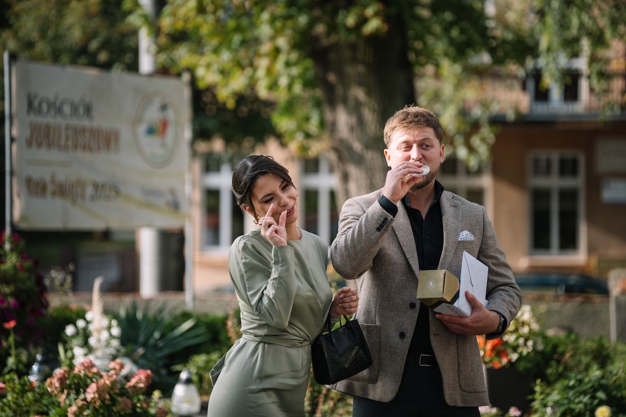 Man and woman in formal attire standing outside a Jubilee Church on a sunny day.