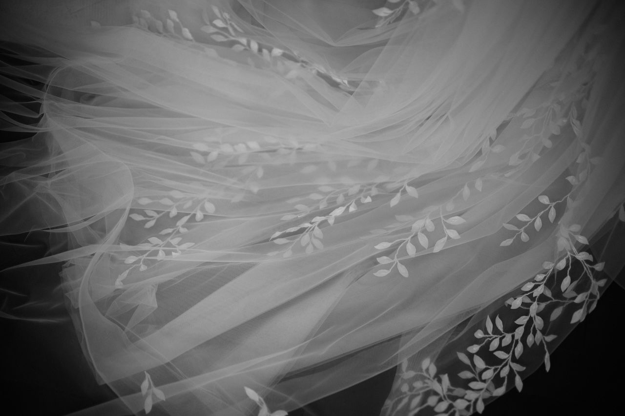 Close-up black and white detail of embroidered floral lace wedding veil texture.