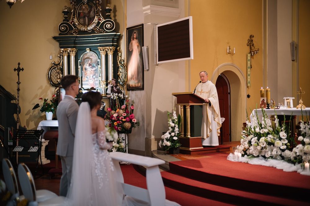 Bride and groom standing at altar during Catholic church wedding ceremony with priest.